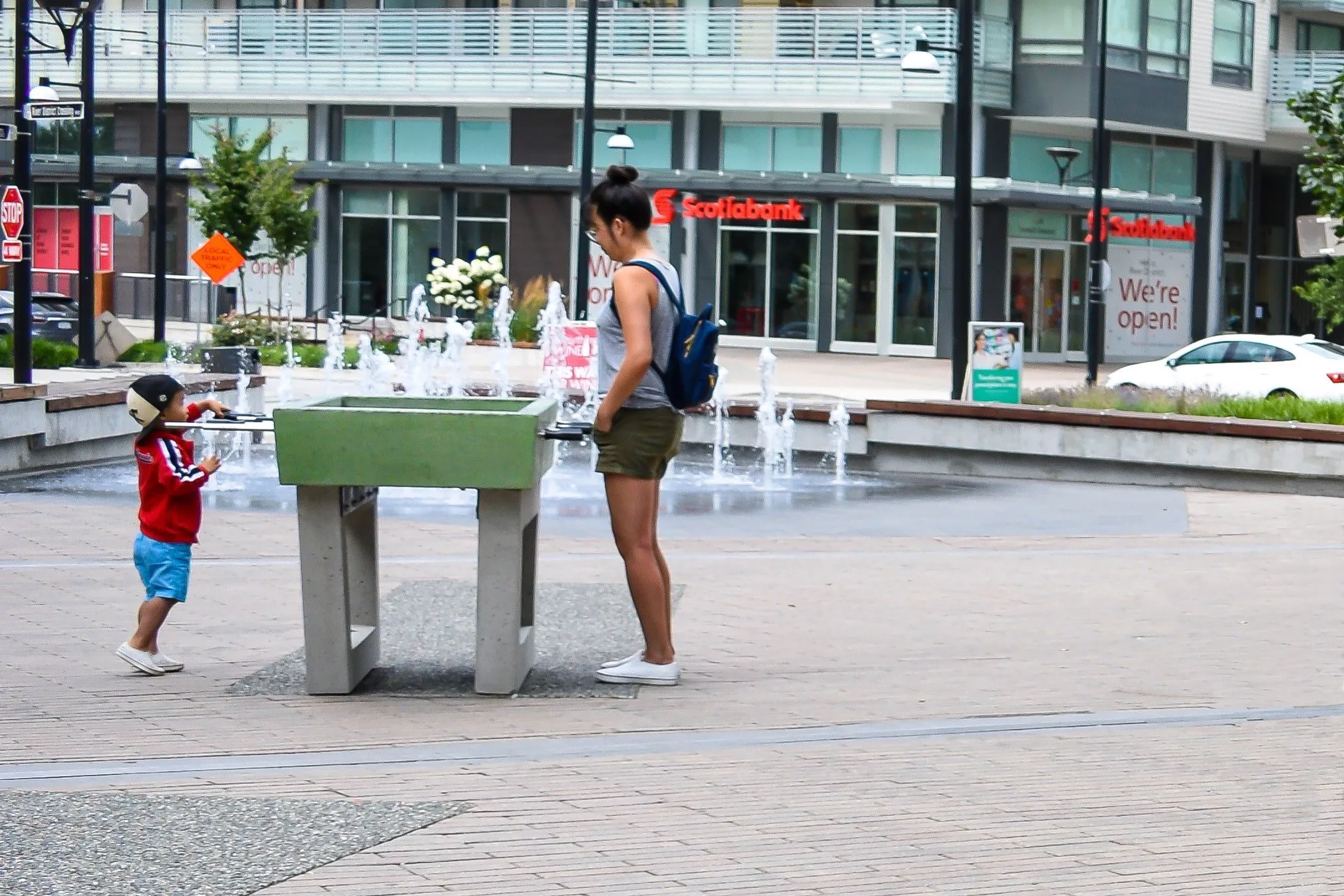 Child playing at a precast concrete outdoor foosball table in a public plaza