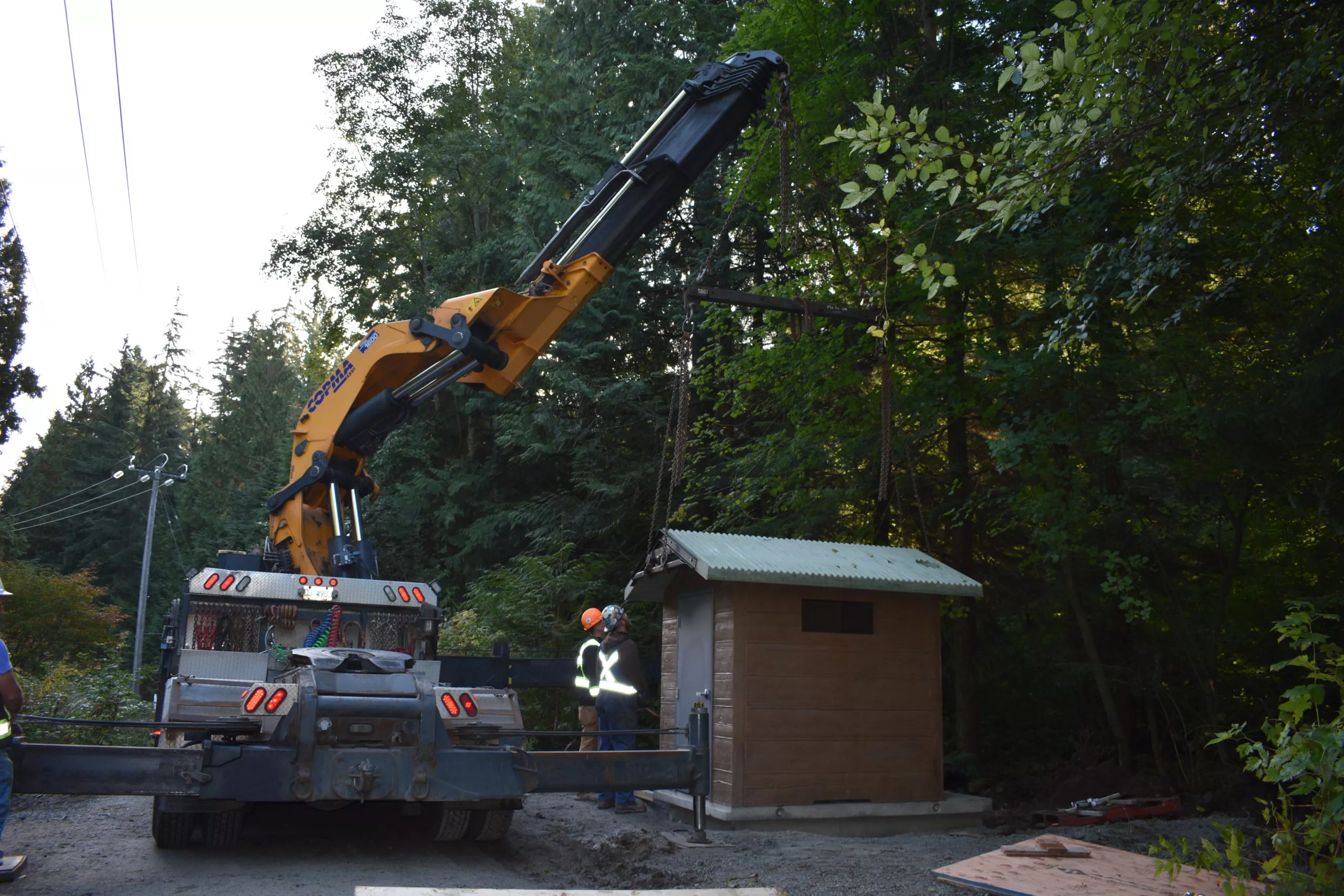 Unloading precast concrete outhouse from delivery truck