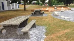 Modern concrete furniture installed in a public park, including benches and picnic tables.